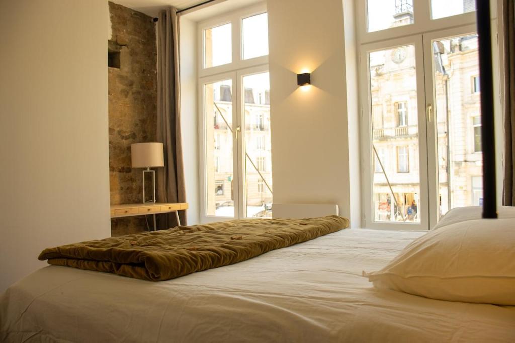 un grand lit dans une chambre avec une grande fenêtre dans l'établissement Suite George - 4 pers proche du coeur historique, à Charleville-Mézières