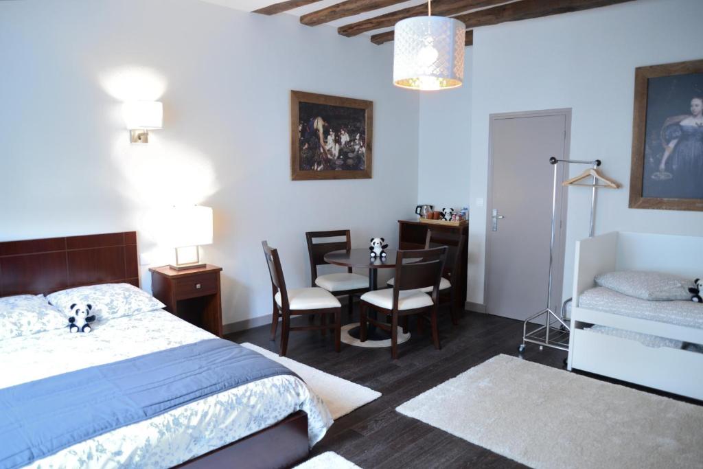 een slaapkamer met een bed en een tafel en stoelen bij Maison du chatelain in Saint-Aignan