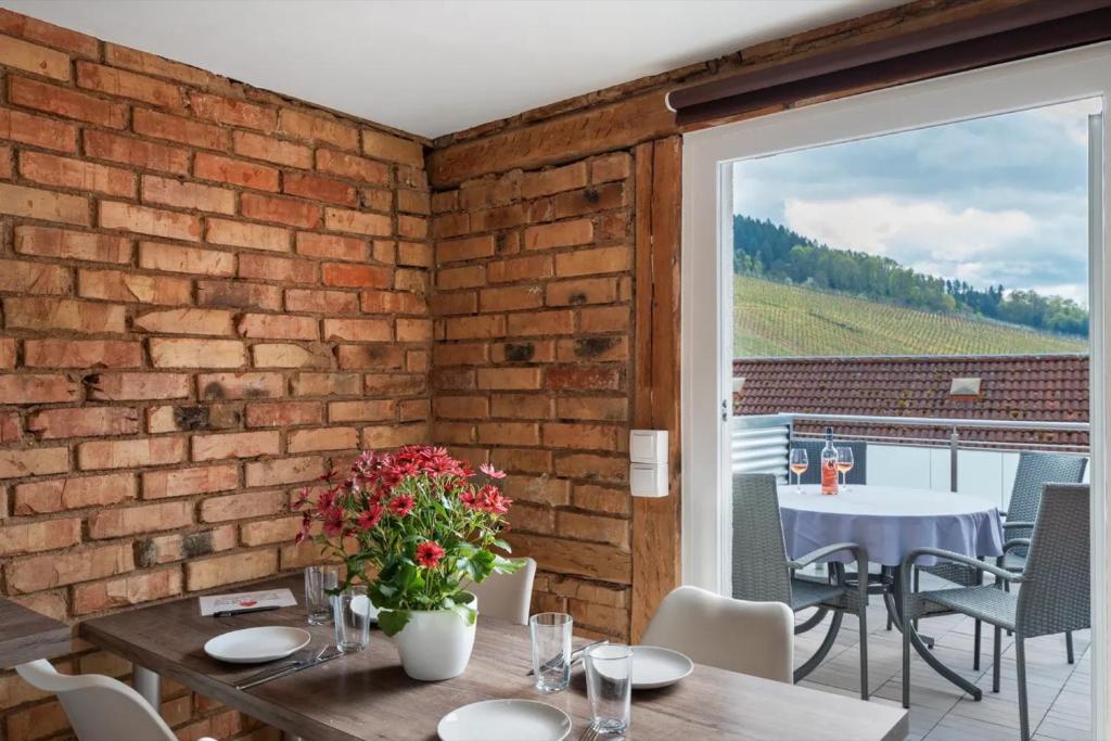 a dining room with a brick wall and a table with flowers at Erlebnis-Bauernhof Heimatliebe in Oberkirch