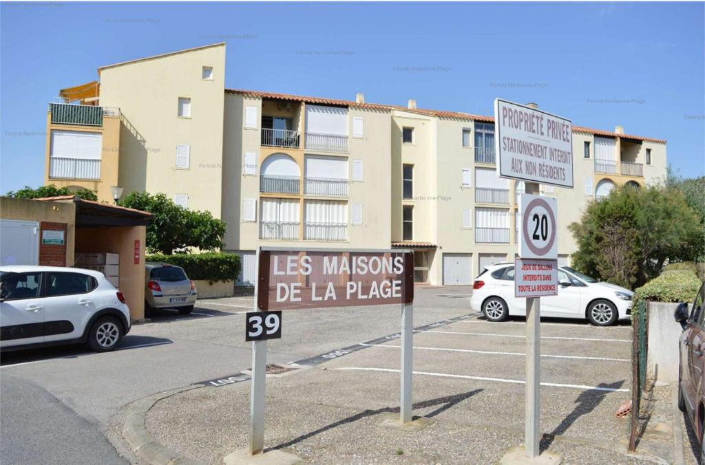 un parking avec des panneaux de signalisation devant un bâtiment dans l'établissement NP170-C018 Appartement 2 pièces Narbonne Plage, à Narbonne-Plage