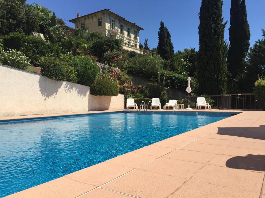 une piscine avec des chaises et un bâtiment en arrière-plan dans l'établissement Saint James Luxury 4 Pers Sea View Parking, à Roquebrune-Cap-Martin