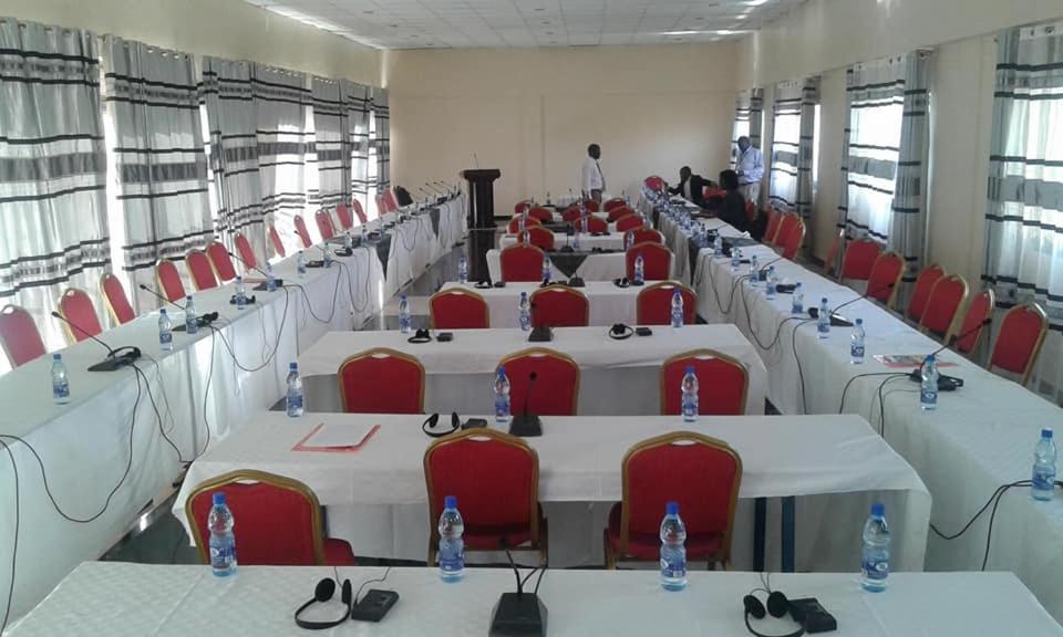 a room with rows of tables and red chairs at ARCH APARTMENTS and HOTEL in Kampala