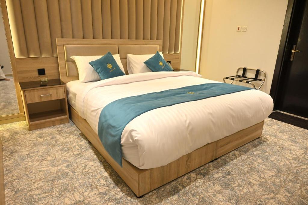 a bedroom with a large bed with blue pillows at شقق افاق إين للشقق المخدومة in Najran