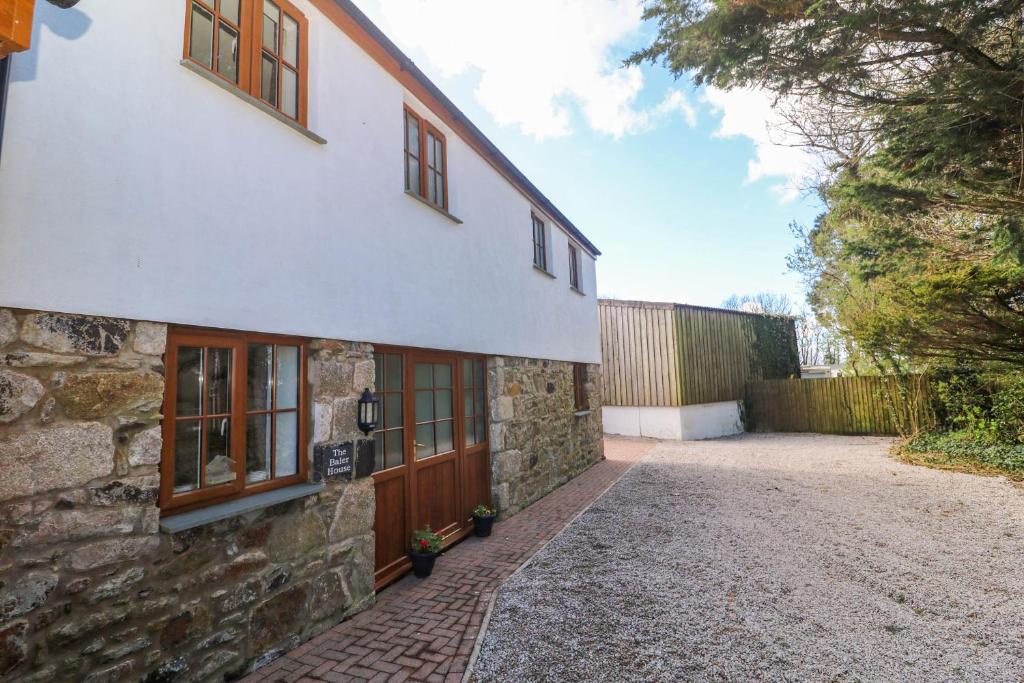 a stone house with wooden doors and a driveway at The Baler House in Hayle
