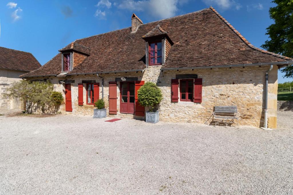 une ancienne maison en pierre avec volets rouges dans l'établissement La Sautie, avec piscine et tennis, à Bars
