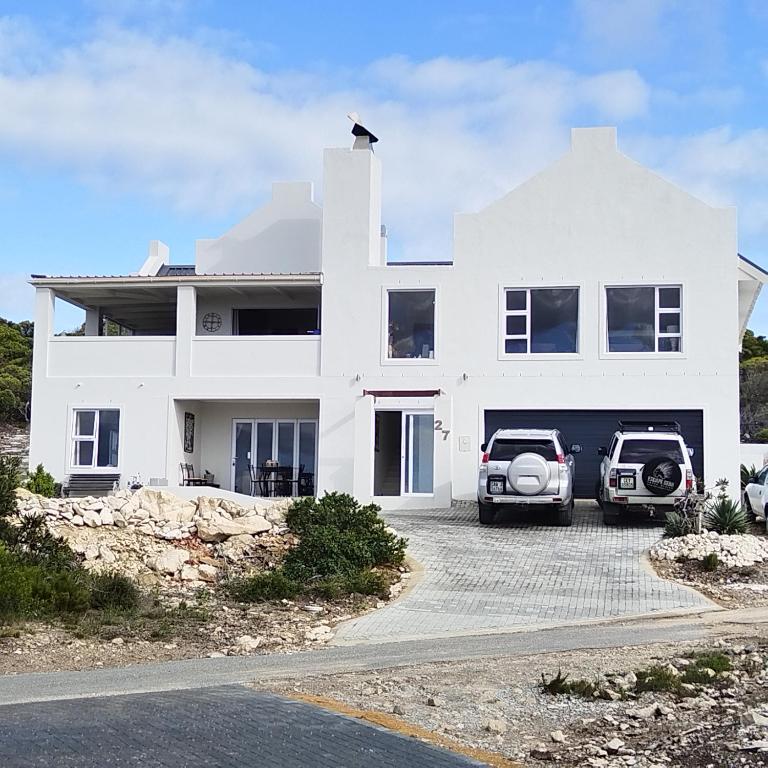 a white house with two cars parked in the driveway at Agulhas Splendour in Agulhas