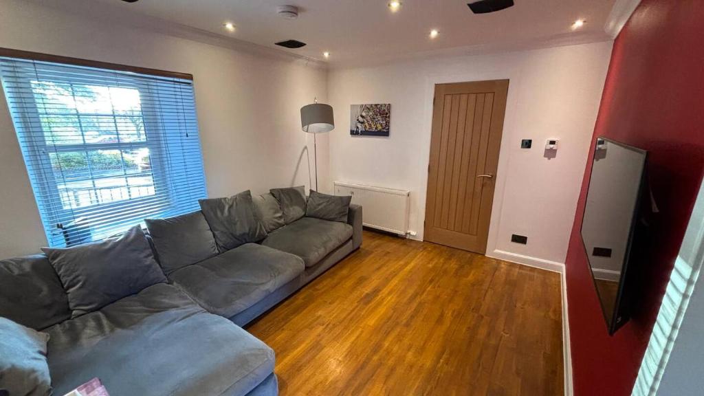 a living room with a gray couch and a large window at Roserin Coorie, Perth - just a few minutes walk from the city centre! in Perth