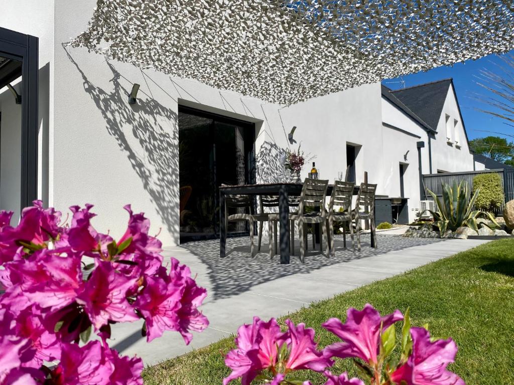 d'une terrasse avec des fleurs roses et une table. dans l'établissement Villa La Grée - 10 min à pied de la plage, à Sarzeau