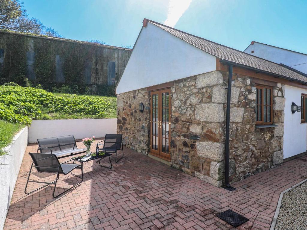 a stone cottage with a table and chairs on a patio at The Coach House in Hayle