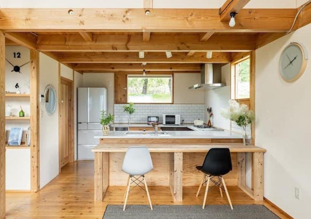 a kitchen with a wooden counter and two chairs at Kitaarupusu ichibō no ie - Vacation STAY 96488v in Omachi