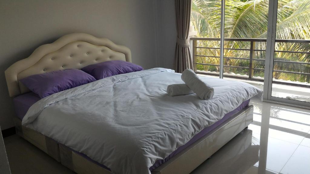 Un dormitorio con una cama con almohadas moradas y una ventana en Aple Homestay en Amphawa