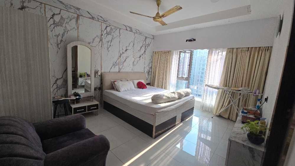 a bedroom with a bed and a couch and a mirror at Duplex Penthouse in Kolkata