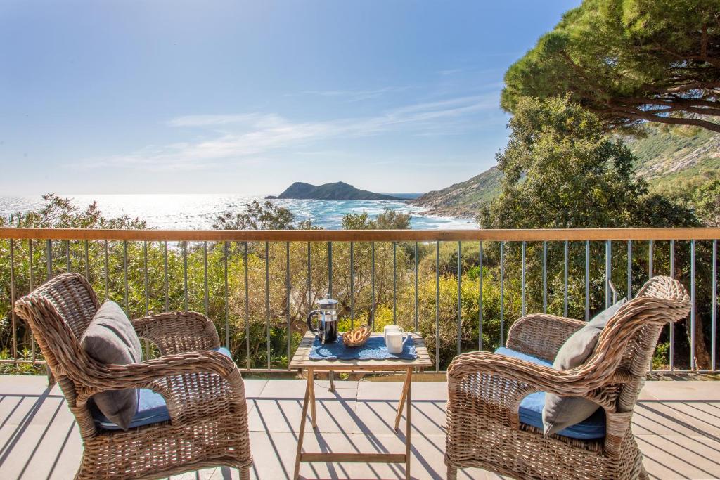 un patio avec deux chaises et une table sur une terrasse dans l'établissement Villa L'ile Bleue, à Ramatuelle