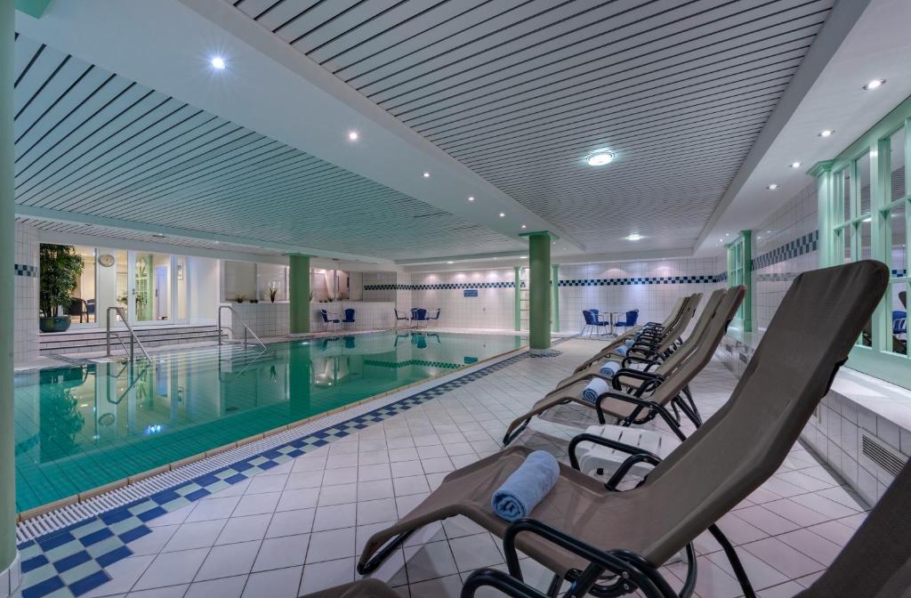 a pool with lounge chairs next to a swimming pool at Hotel Aquamarin in Kühlungsborn