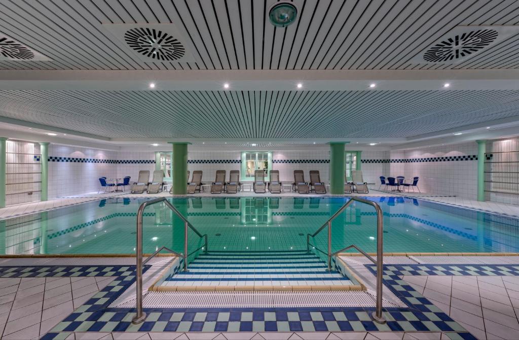 een groot zwembad met stoelen in een gebouw bij Hotel Aquamarin in Kühlungsborn