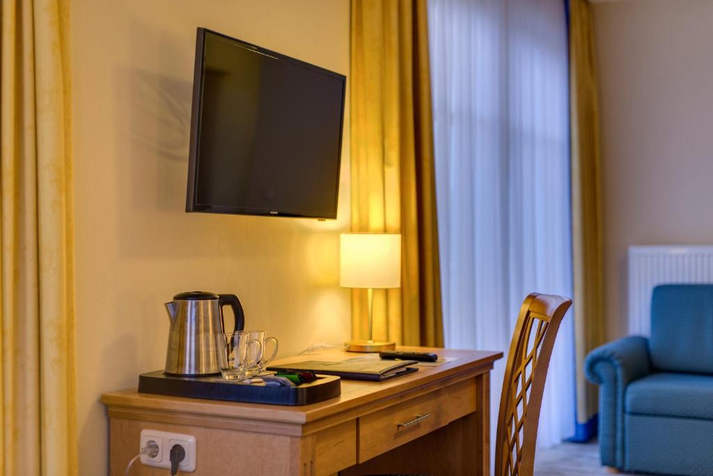 a hotel room with a desk with a television on a wall at Hotel Aquamarin in Kühlungsborn