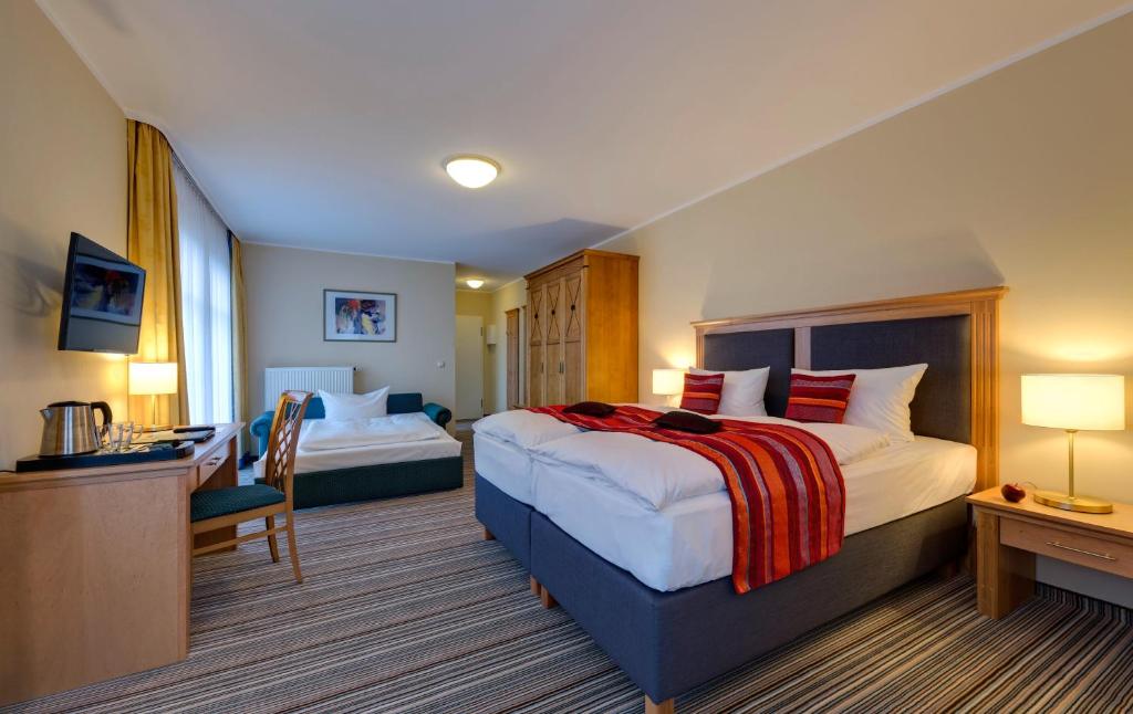 a hotel room with a large bed and a desk at Hotel Aquamarin in Kühlungsborn