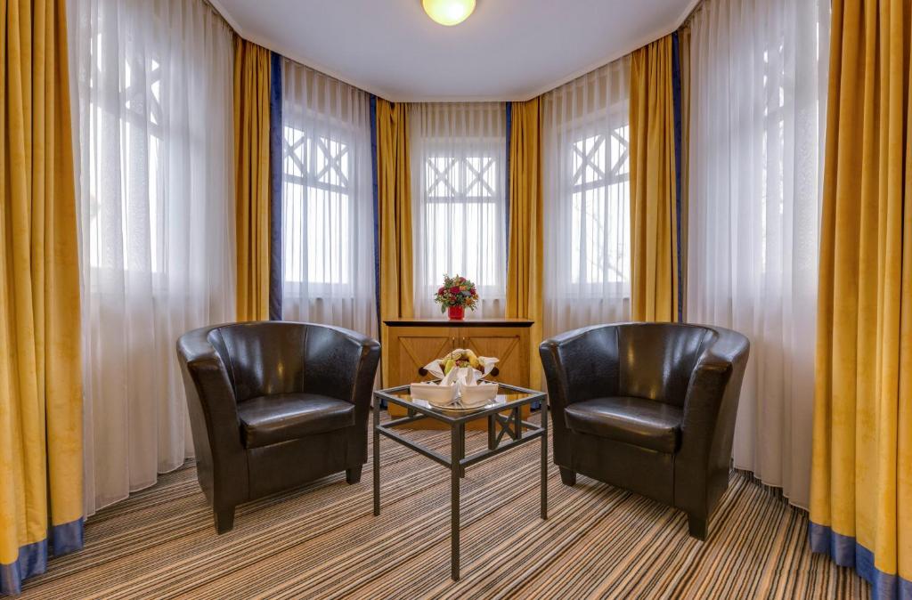 two chairs and a table in a room with windows at Hotel Aquamarin in Kühlungsborn