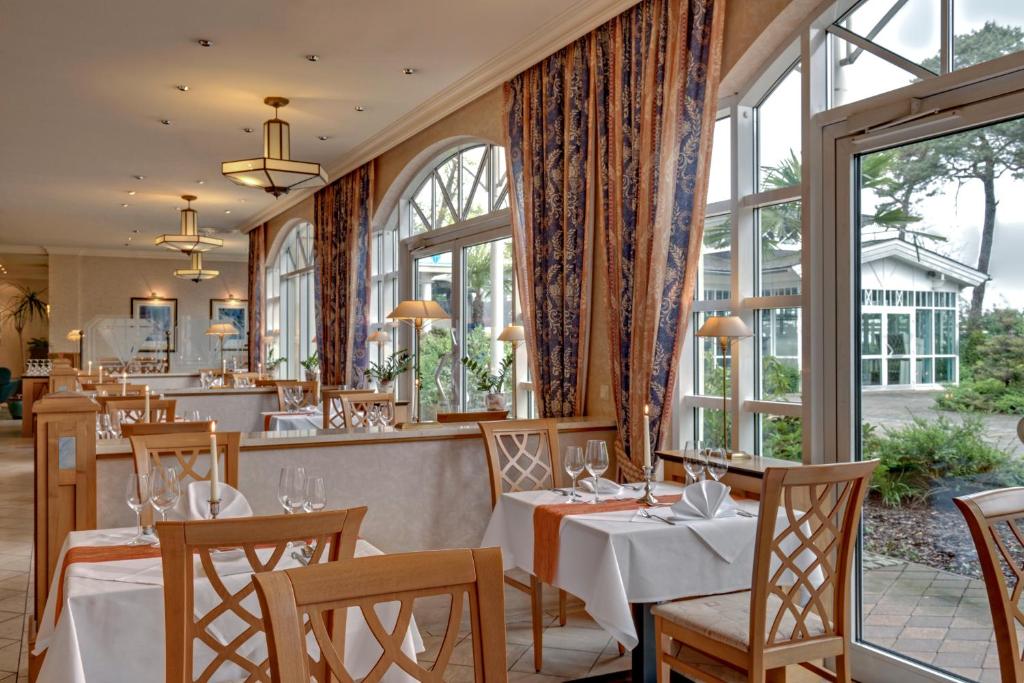 a restaurant with tables and chairs and windows at Hotel Aquamarin in Kühlungsborn