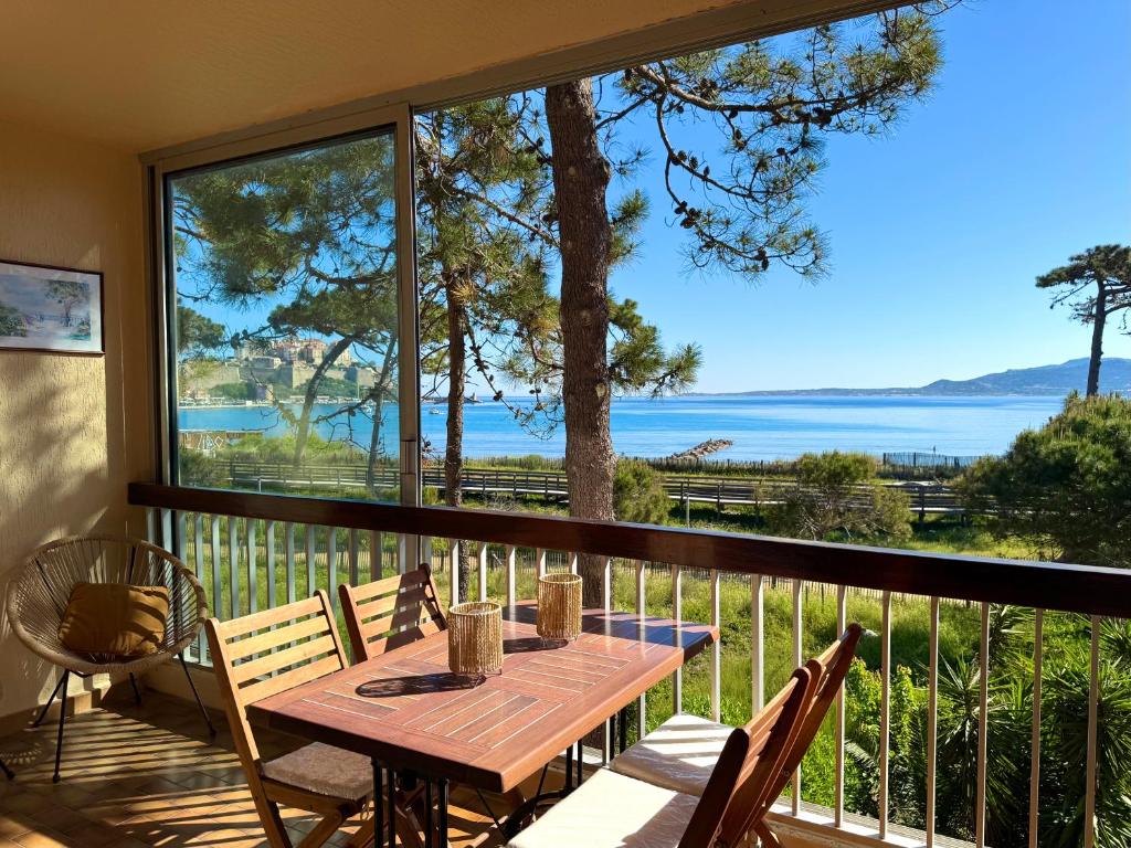 une table sur un balcon avec vue sur l'eau dans l'établissement Logement pieds dans l'eau avec vue mer exceptionnelle, à Calvi