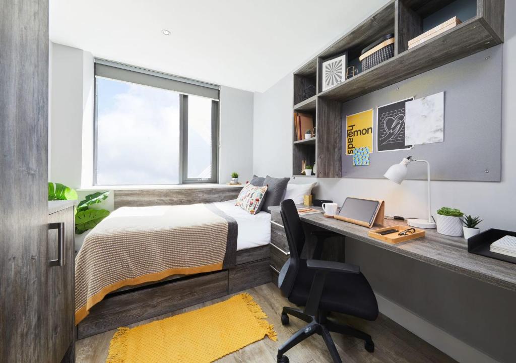 a bedroom with a bed and a desk with a laptop at For Students Only - Collegiate Crown Place Cardiff in Cardiff