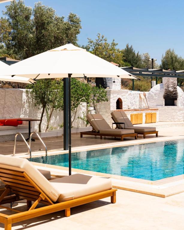 ein Pool mit zwei Liegestühlen und einem Sonnenschirm in der Unterkunft Tulu Datca in Yakaköy
