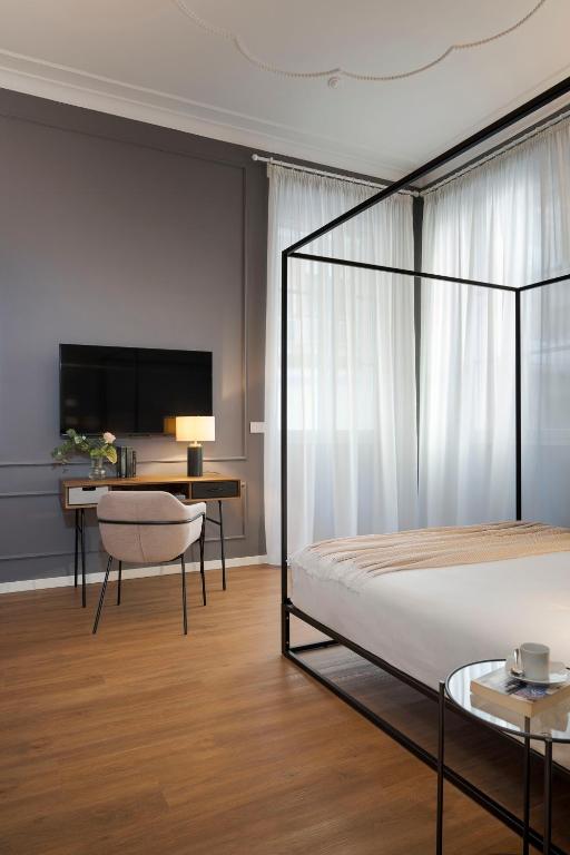 una camera con letto, scrivania e TV di Elysium Boutique Apartments - Catania a Catania
