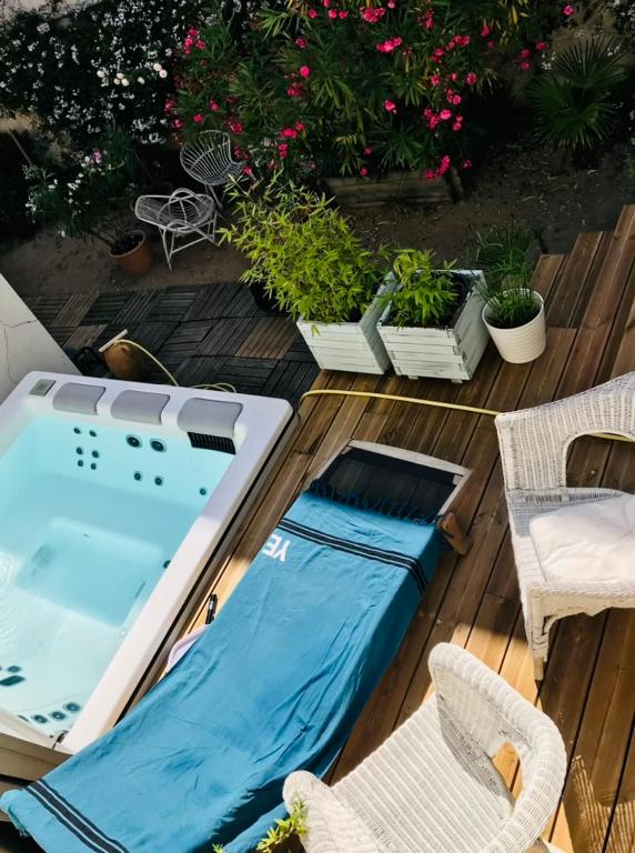 un bain à remous et des chaises sur une terrasse avec des plantes dans l'établissement Les Vagues, à Saint-Gilles-Croix-de-Vie