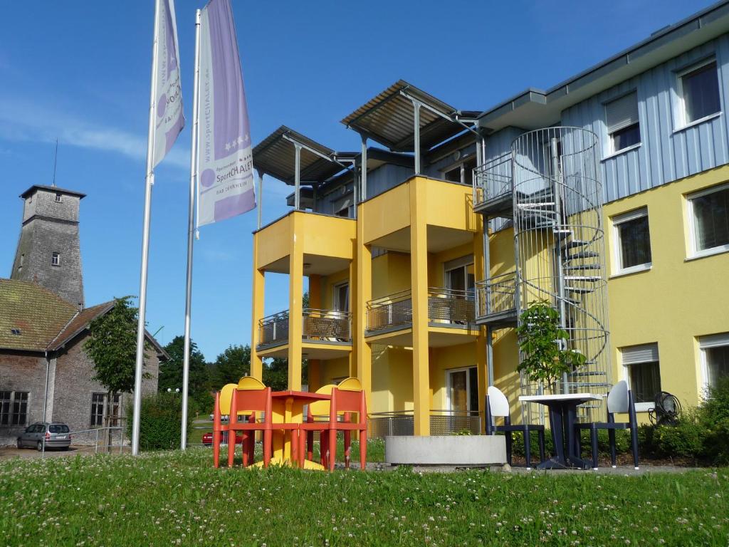 um edifício amarelo com cadeiras coloridas em frente em Apartmenthaus SportCHALET em Bad Dürrheim