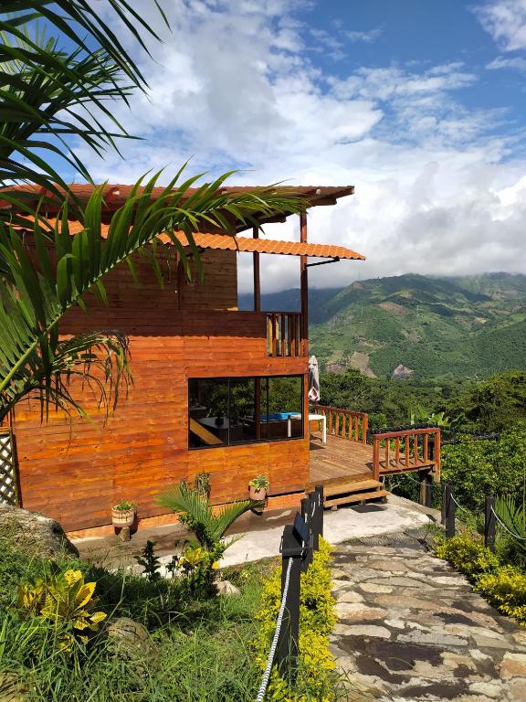 a wooden house with a deck and mountains in the background at Cabaña con vistas a la montaña in Cachipay