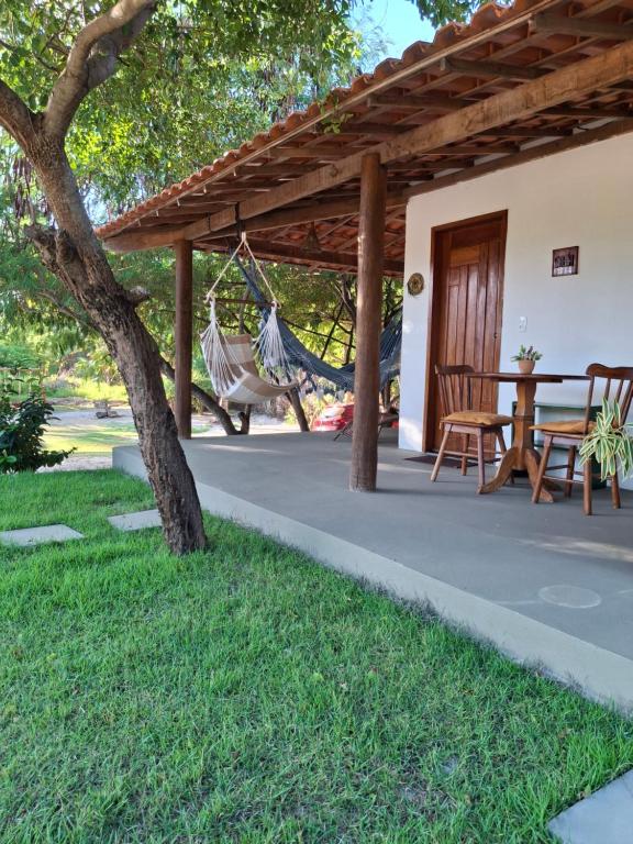 a porch with a hammock and a house at Recanto Verde - Praia de Santo Antônio in Diogo