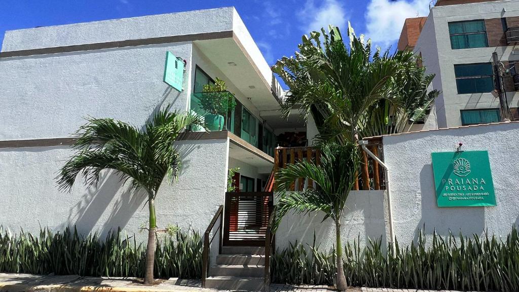 a building with palm trees in front of it at Pousada Praiana in Porto De Galinhas
