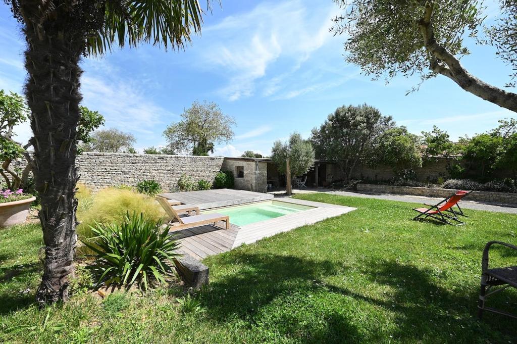 une cour avec une piscine et un arbre dans l'établissement 999 Le Moulin - Pool and nature, à La Couarde-sur-Mer