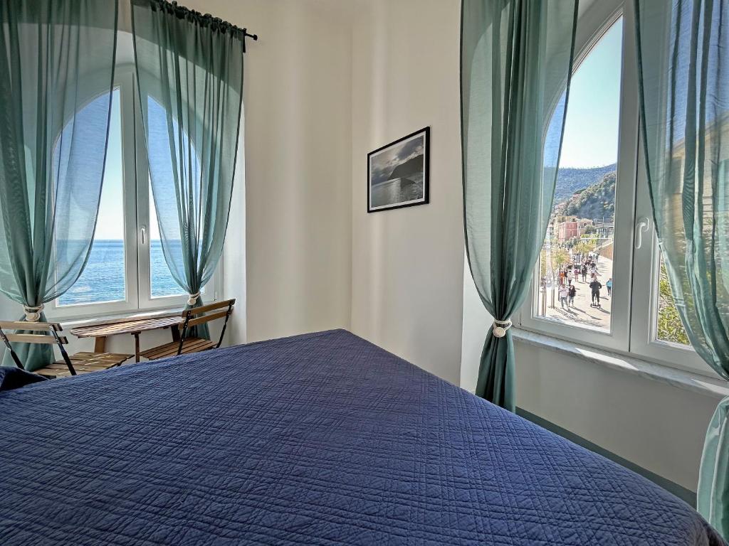 a bedroom with a blue bed and large windows at Hotel Meublè Agavi in Monterosso al Mare