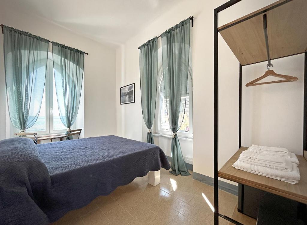 a bedroom with a blue bed and two windows at Hotel Meublè Agavi in Monterosso al Mare