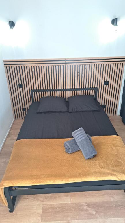 un lit avec une tête de lit en bois et une paire de serviettes dans l'établissement Nice studio near Disneyland and Paris with Parking, à Bussy-Saint-Georges