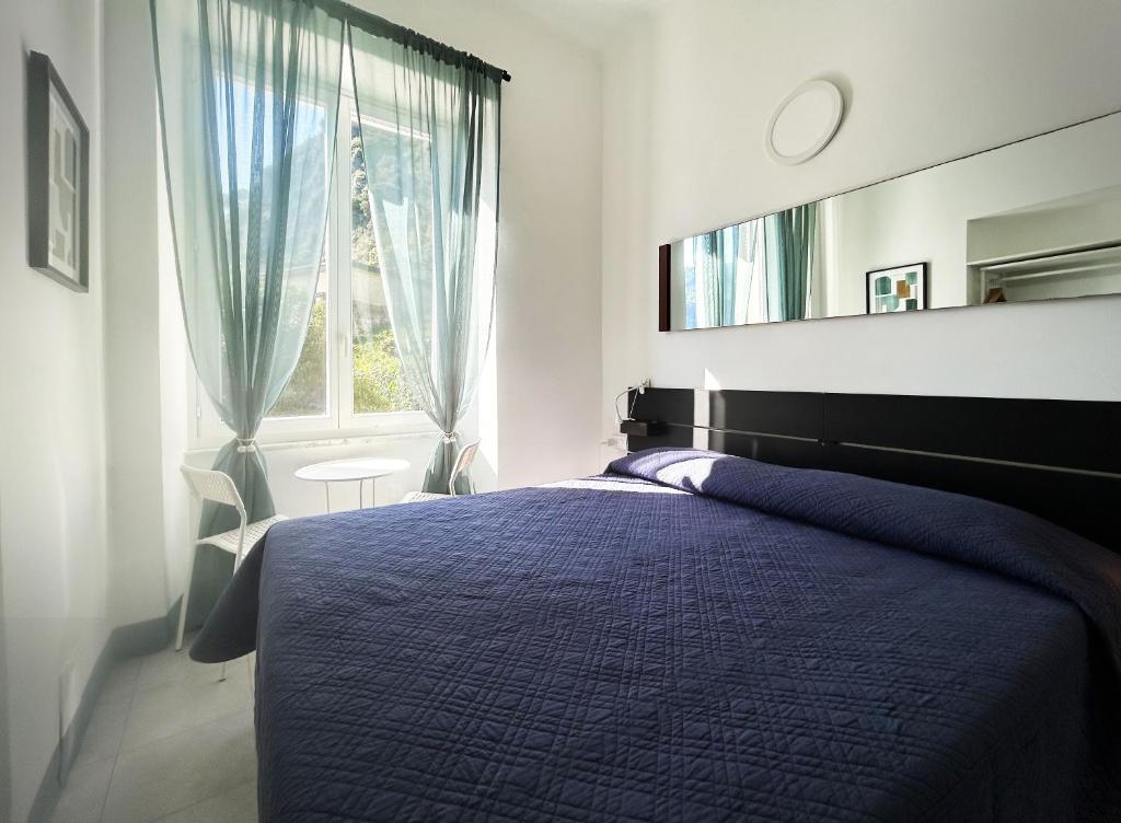 a bedroom with a blue bed and a mirror at Hotel Meublè Agavi in Monterosso al Mare