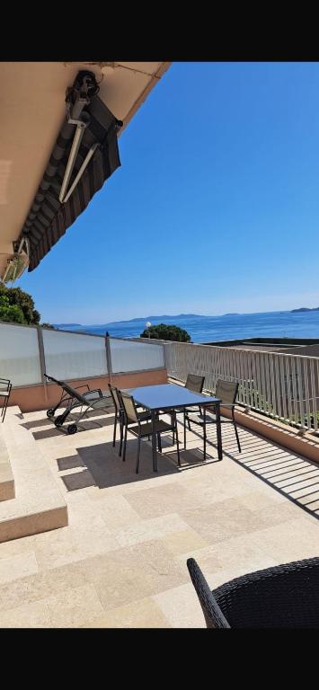 un patio avec une table et des chaises et l'océan dans l'établissement La fossette, au Lavandou