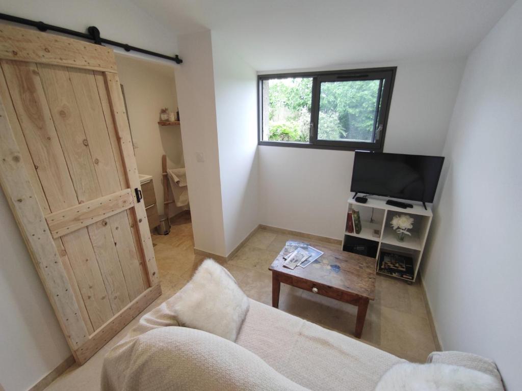 a living room with a couch and a tv and a door at La croisée des destins in Viviers