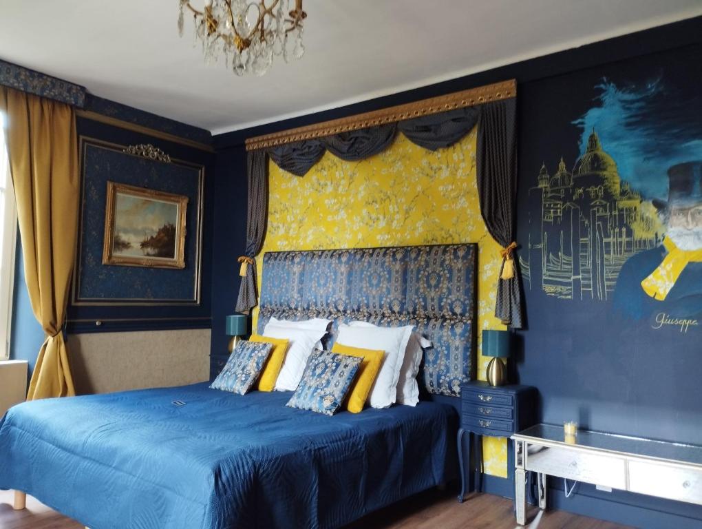 a bedroom with a blue bed with a yellow wall at Le PALAZZO YES in Woël