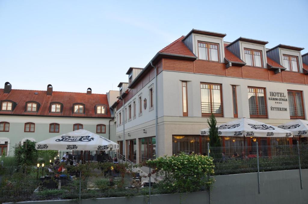 a large building with an umbrella in front of it at Hotel Három Gúnár in Kecskemét