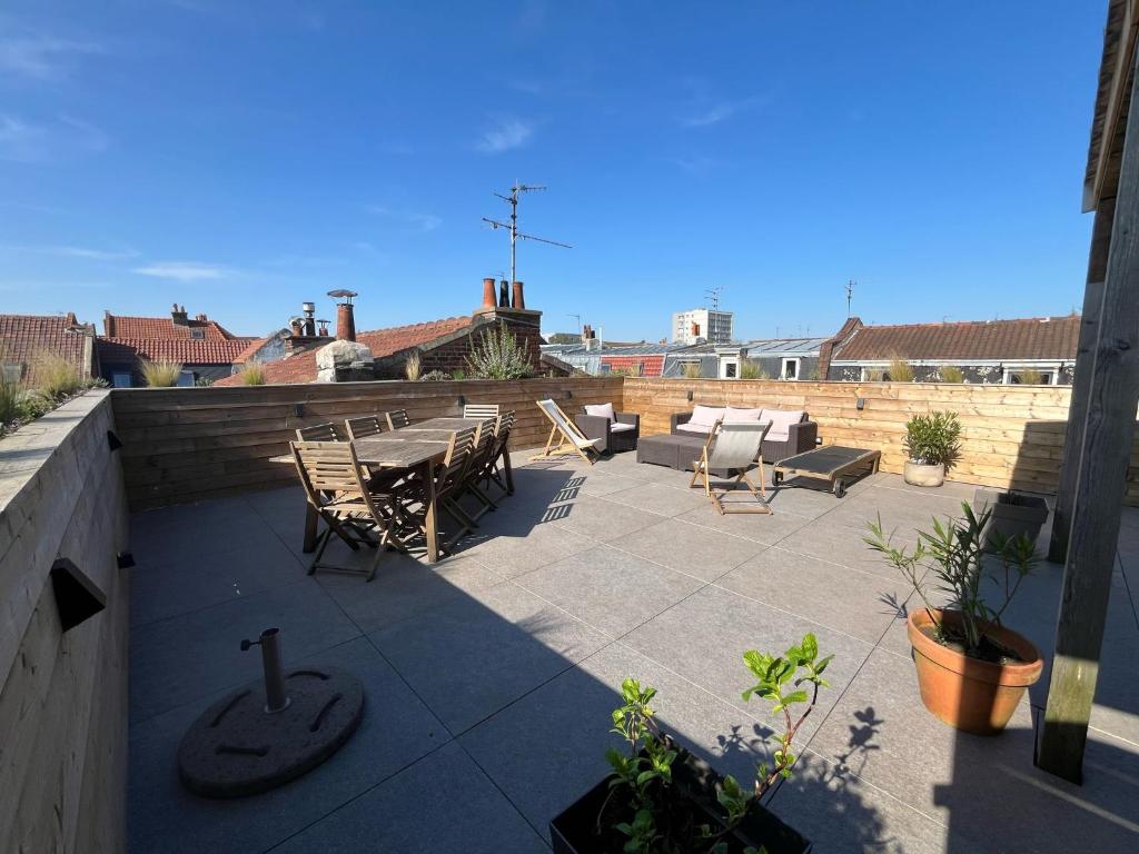 un patio avec une table et des chaises sur un toit dans l'établissement Appartement de ville - Lille Lambersart, à Lambersart
