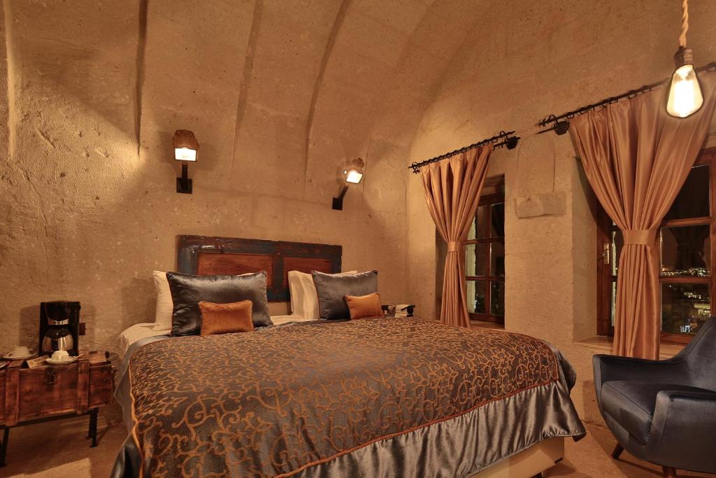 a bedroom with a large bed and a chair at The Owl Cave Hotel in Goreme