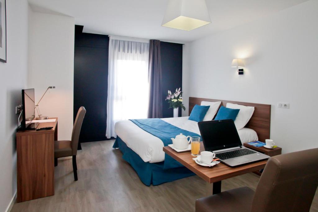 a hotel room with a bed and a desk with a laptop at Résidence Odalys Paris Rueil in Rueil-Malmaison