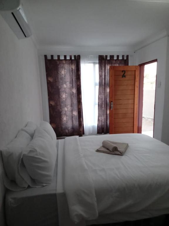 a bedroom with a white bed with two towels on it at Zindi Zindiza Lodge in Sandrivier