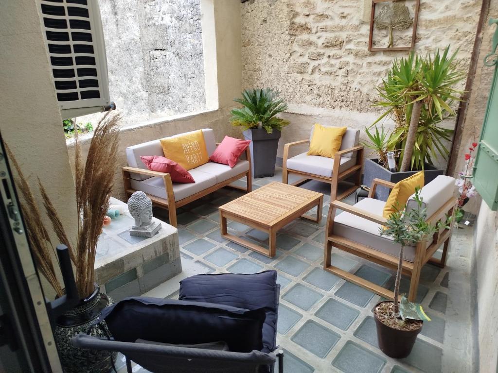 une terrasse avec des canapés, des chaises et des plantes en pot dans l'établissement Maison de village avec terrasse, à Aubais