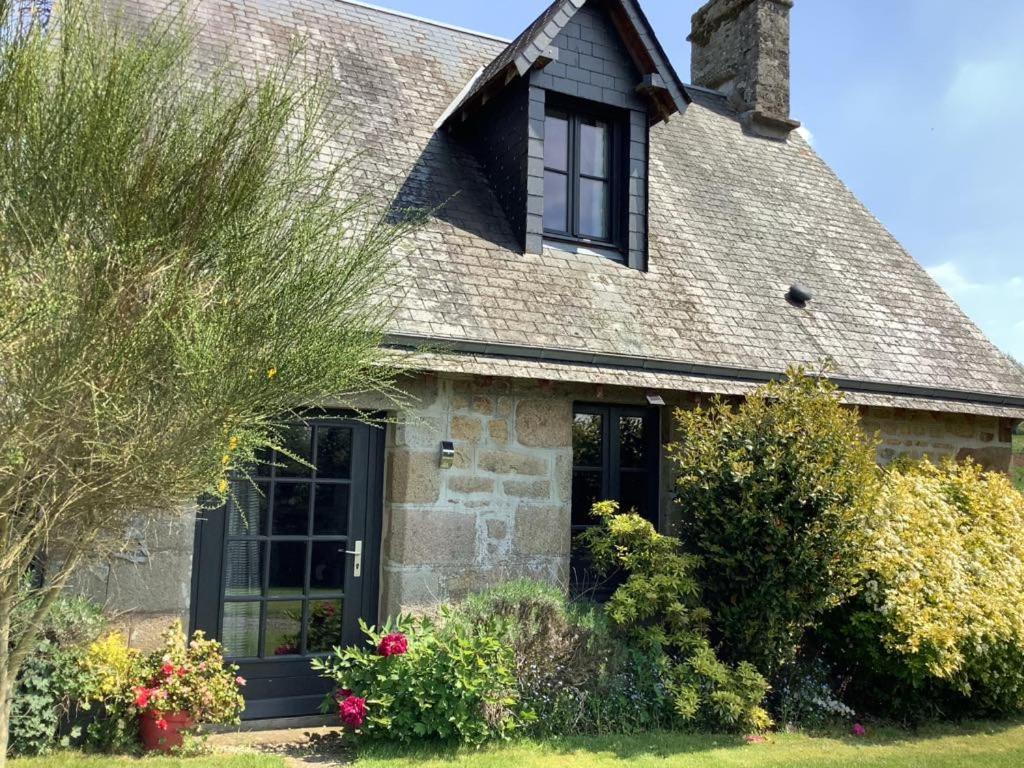 une maison en pierre avec des fenêtres noires et des buissons dans l'établissement Romantic Cottage, à Vire