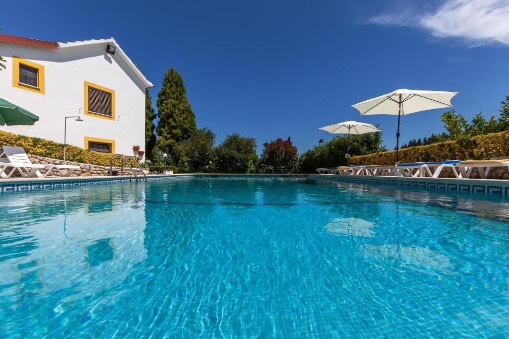 a swimming pool with blue water in front of a building at Quinta de Vale Escuro in Lousã