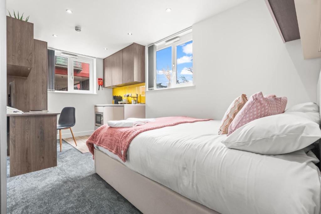 a bedroom with a large white bed and a kitchen at Contemporary Comfort Steps from Ricoh Arena in Coventry