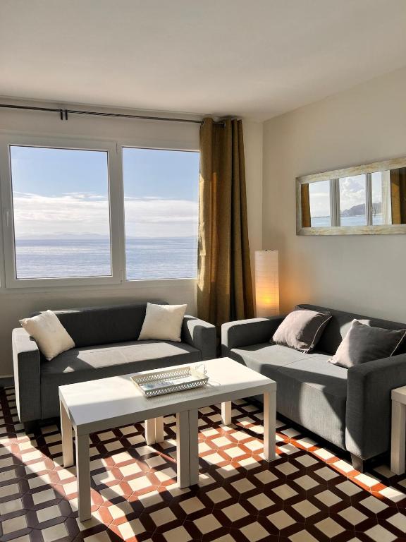 a living room with two couches and a table at Duplex B Vacaciones en el mar in Ribeira